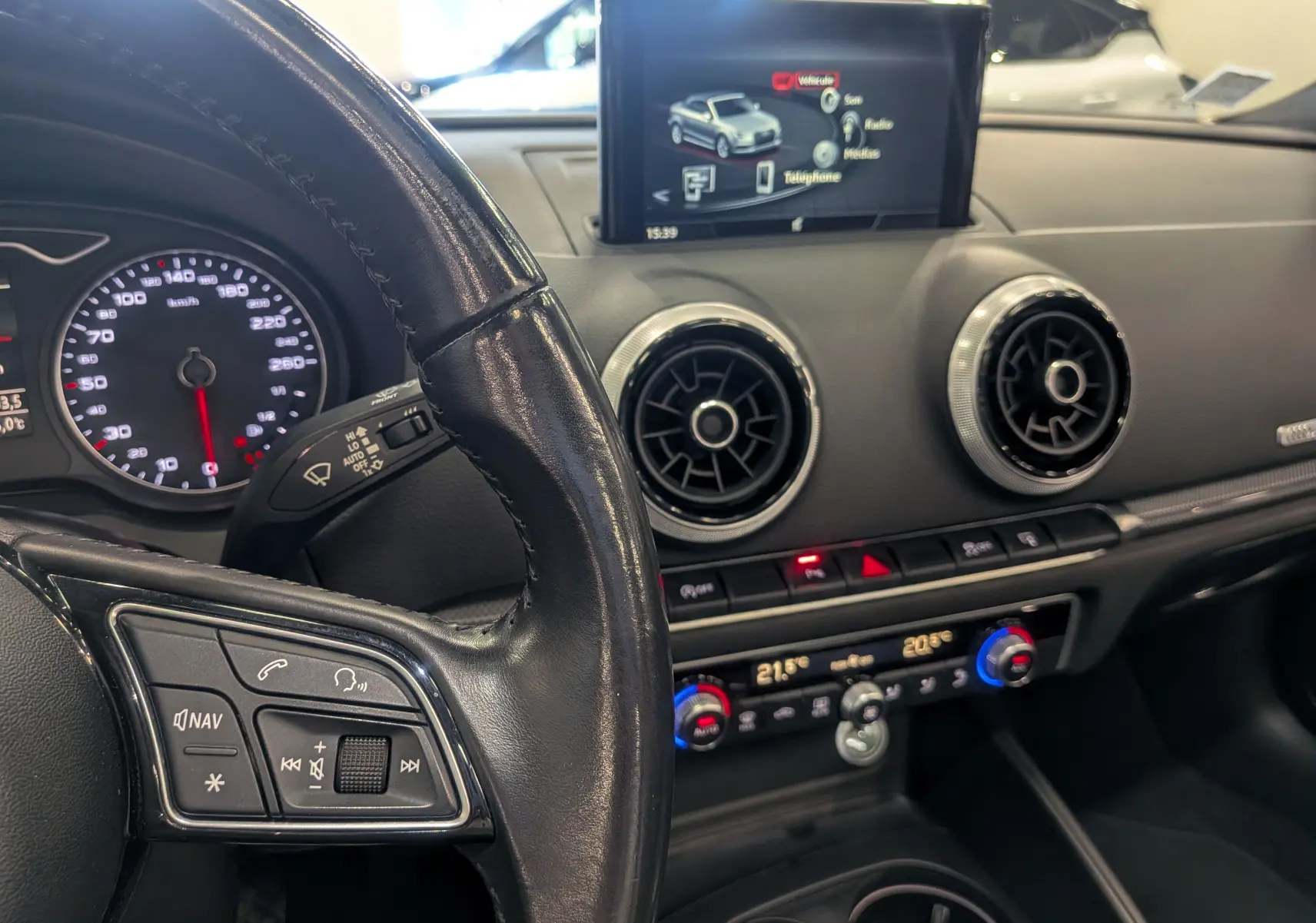 Vue intérieure centrée sur le volant et la console centrale de l'Audi A3 Cabriolet 2017, avec écran multimédia et commandes climatisation.