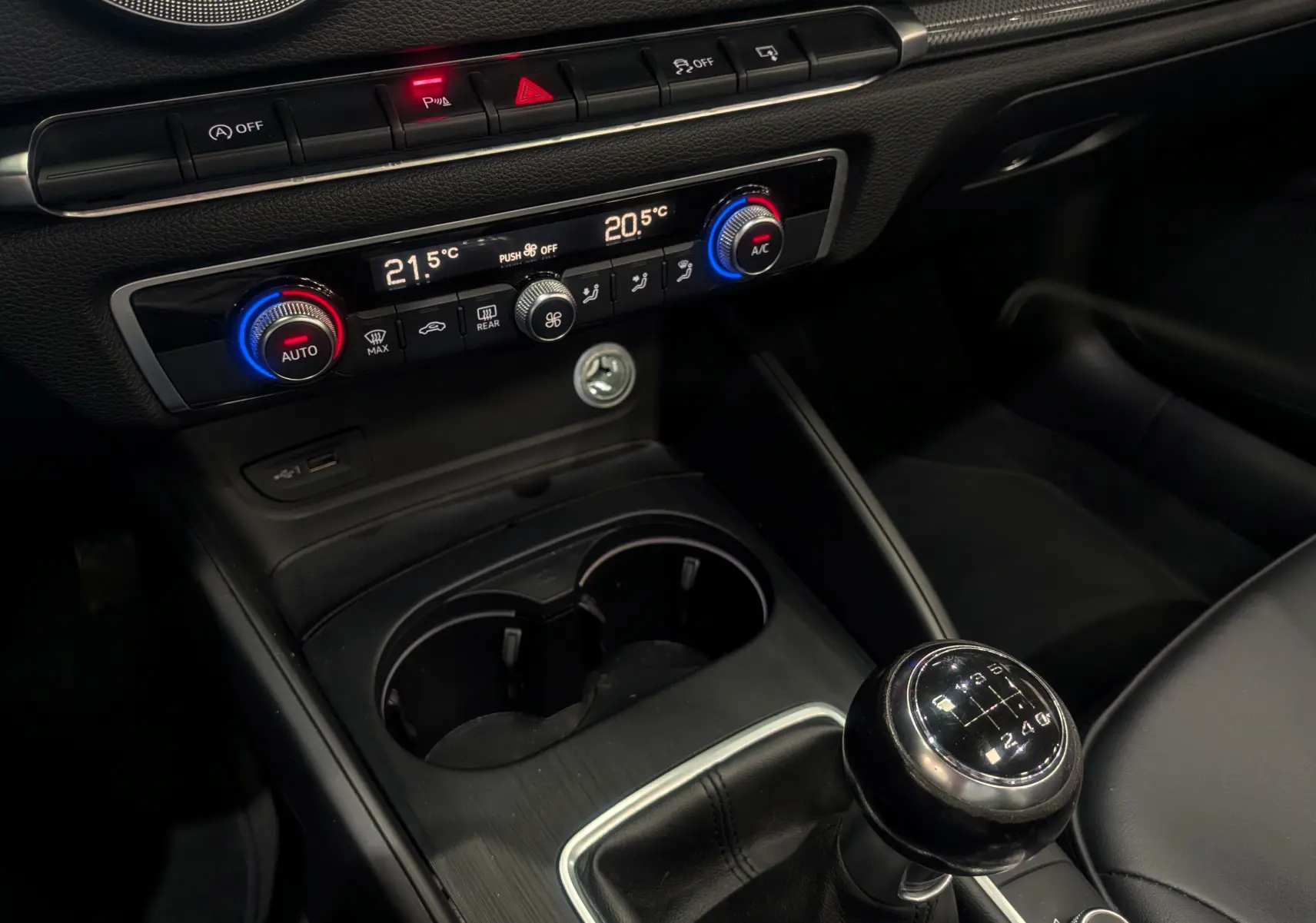 Vue rapprochée de la console centrale noire de l'Audi A3 Cabriolet 2017 avec boîte manuelle et commandes de climatisation digitales.