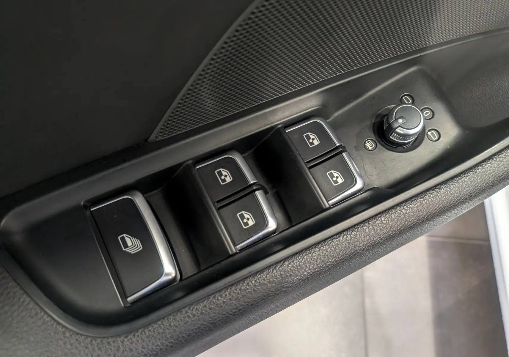 Gros plan sur les commandes des vitres électriques et réglage des rétroviseurs côté conducteur d'une Audi A3 Cabriolet blanc 2017.