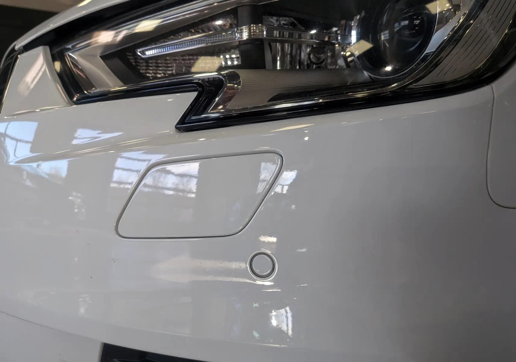 Gros plan sur le phare avant droit blanc d'une Audi A3 Cabriolet 2017 avec capteur de stationnement intégré.