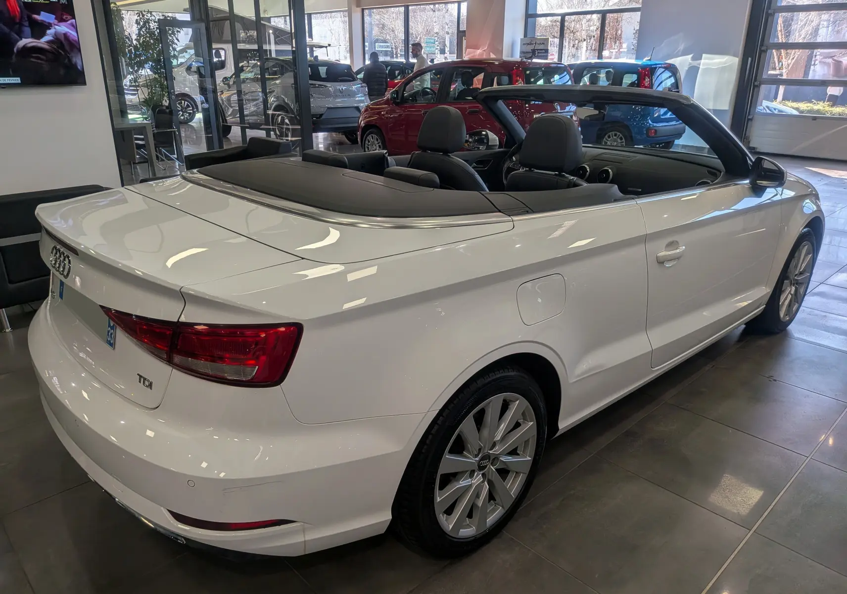 Audi A3 Cabriolet blanc vue 3/4 arrière droit, toit ouvert, intérieur noir, en showroom lumineux.