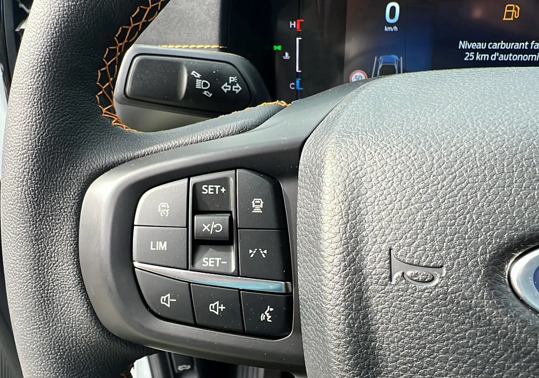 Gros plan sur le volant multifonctions noir du Ford Ranger blanc glacier, avec commandes de régulateur et écran digital en arrière-plan.