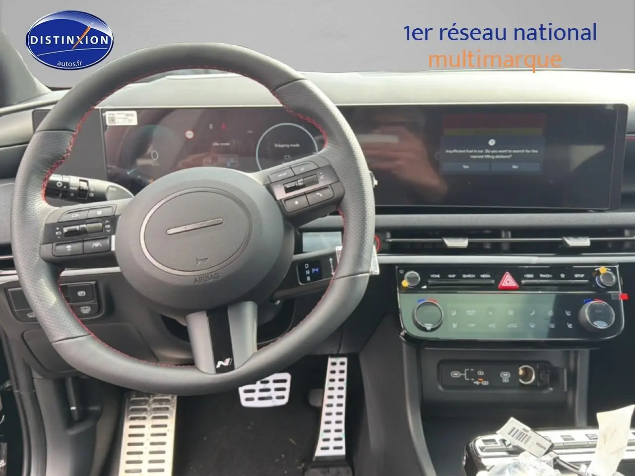 Vue intérieure centrée sur le volant cuir noir avec surpiqûres rouges et tableau de bord numérique du Hyundai Tucson 2026.