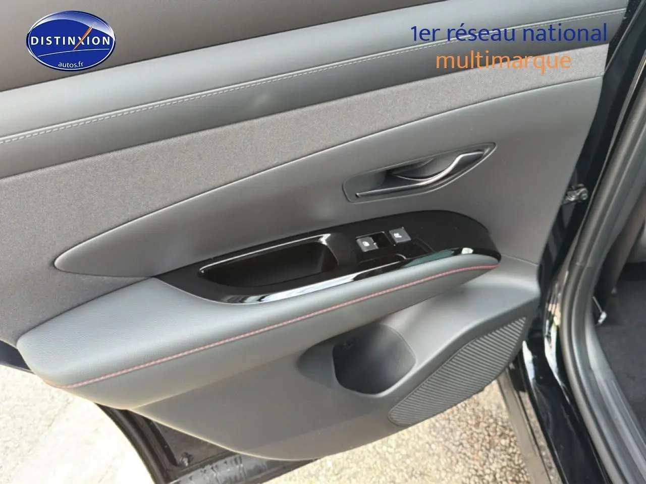Gros plan sur la porte avant gauche noire du Hyundai Tucson 2026 avec commandes de vitres et poignée intégrée.