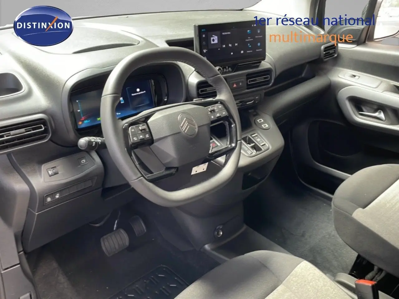 Vue intérieure centrée sur le volant multifonction et tableau de bord numérique du Citroën Berlingo 2026, finition tissu noir.
