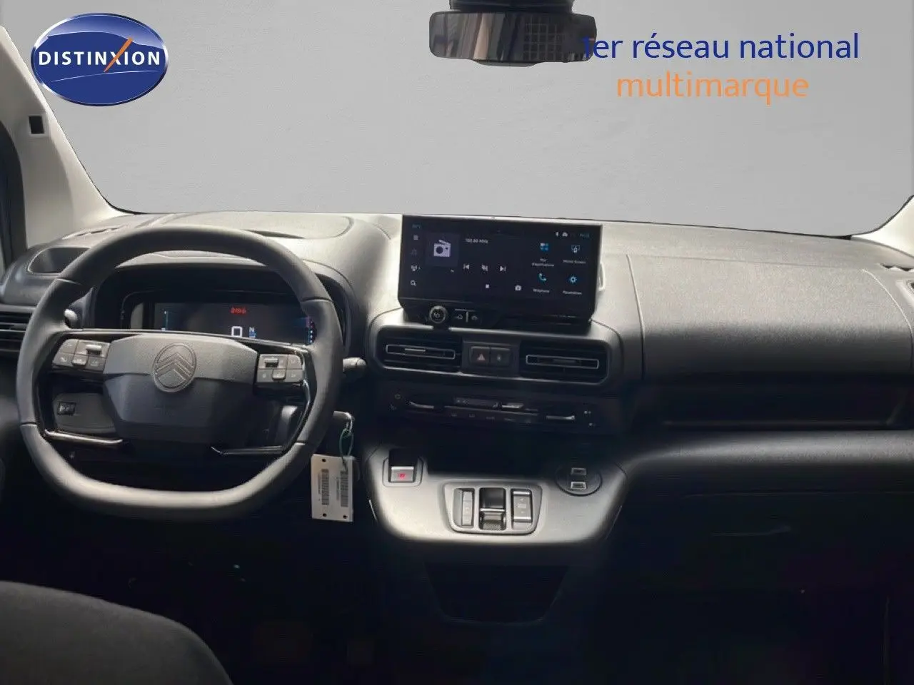 Vue intérieure frontale du poste de conduite du Citroën Berlingo 2026, tableau de bord et volant noirs avec écran tactile central.
