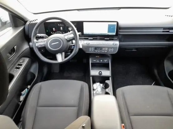 Vue intérieure avant du Hyundai Kona 2024, tableau de bord moderne avec écran tactile et volant multifonction noir.