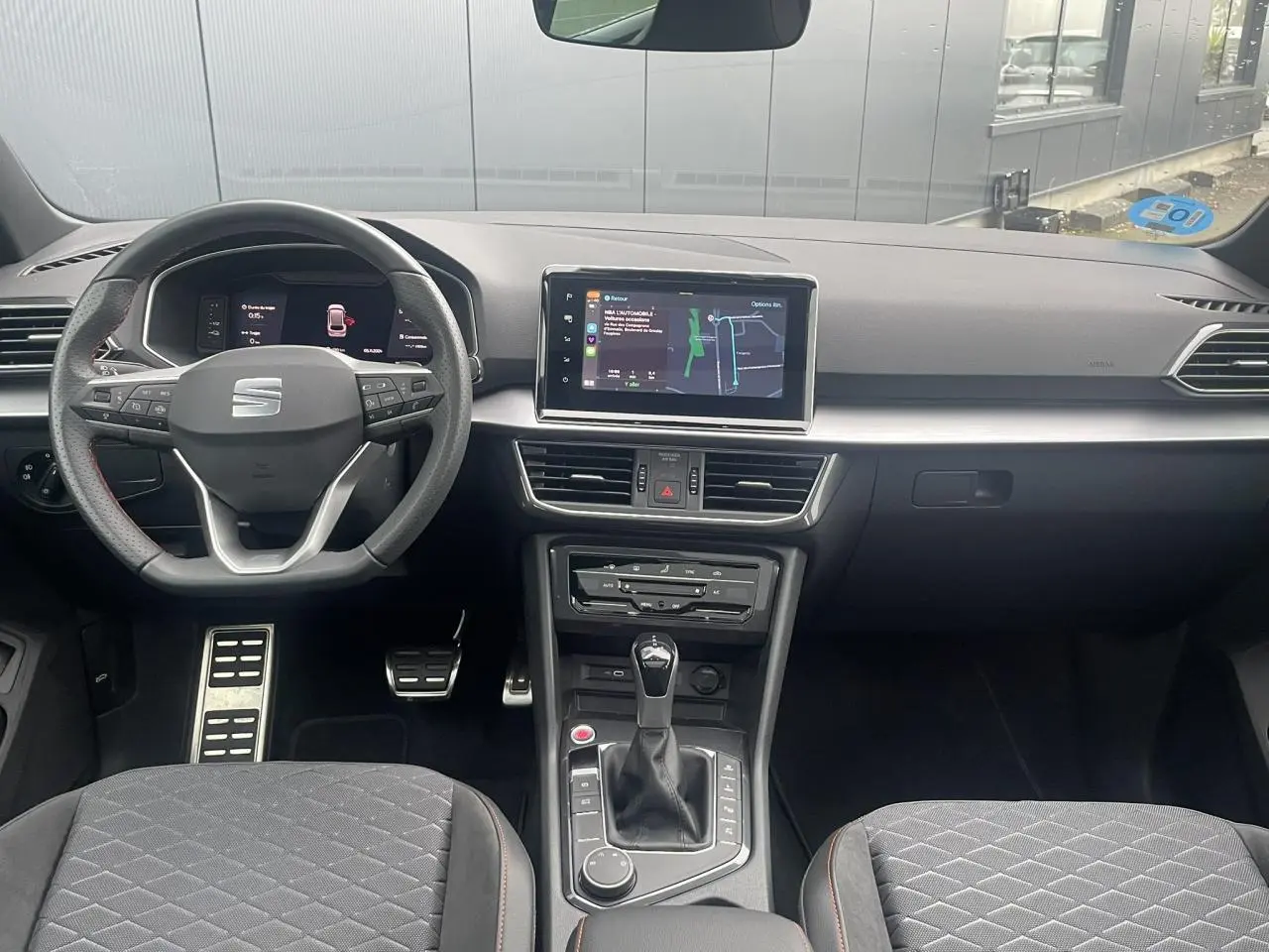 Intérieur du SEAT Tarraco 2024 avec tableau de bord moderne, volant sport et console centrale vue de face.