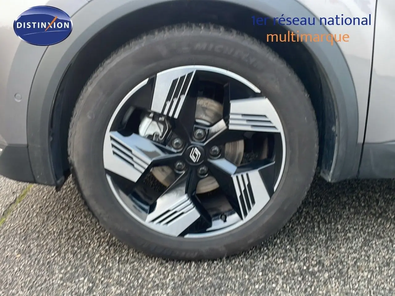 Gros plan sur la roue avant droite du Renault Symbioz gris Cassiopée métal avec jante alliage au design géométrique bicolore.