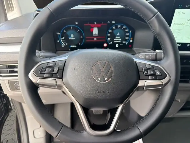 Gros plan sur le volant multifonction noir du Volkswagen Transporter ProCab 2026 avec tableau de bord numérique en arrière-plan.