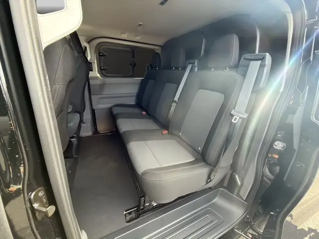 Vue intérieure côté droit du Volkswagen Transporter ProCab 2026 noir, montrant la banquette arrière 3 places en tissu rayé.