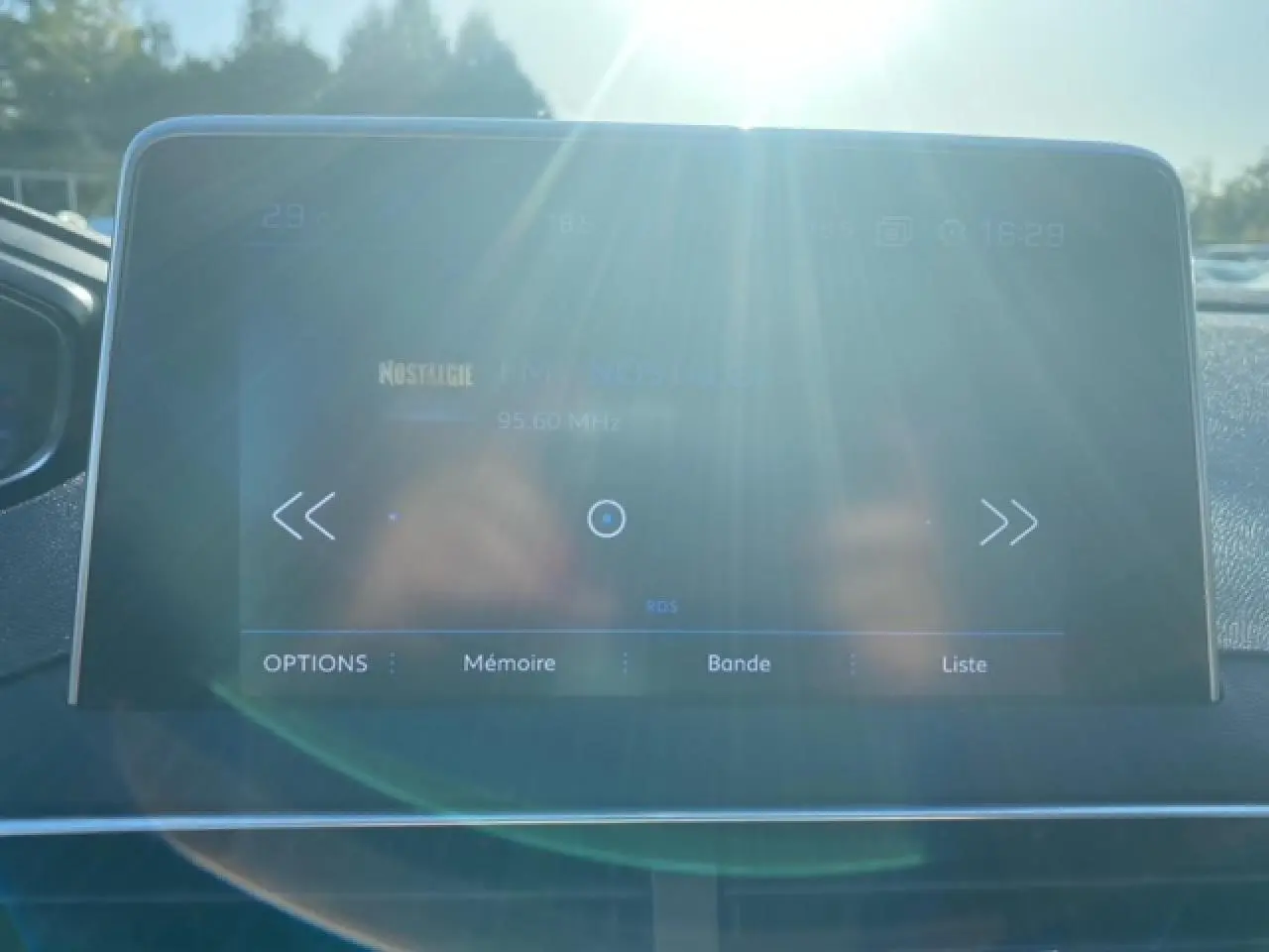 Écran tactile central du Peugeot 3008 2018 avec affichage radio, lumière du soleil et reflet visibles.