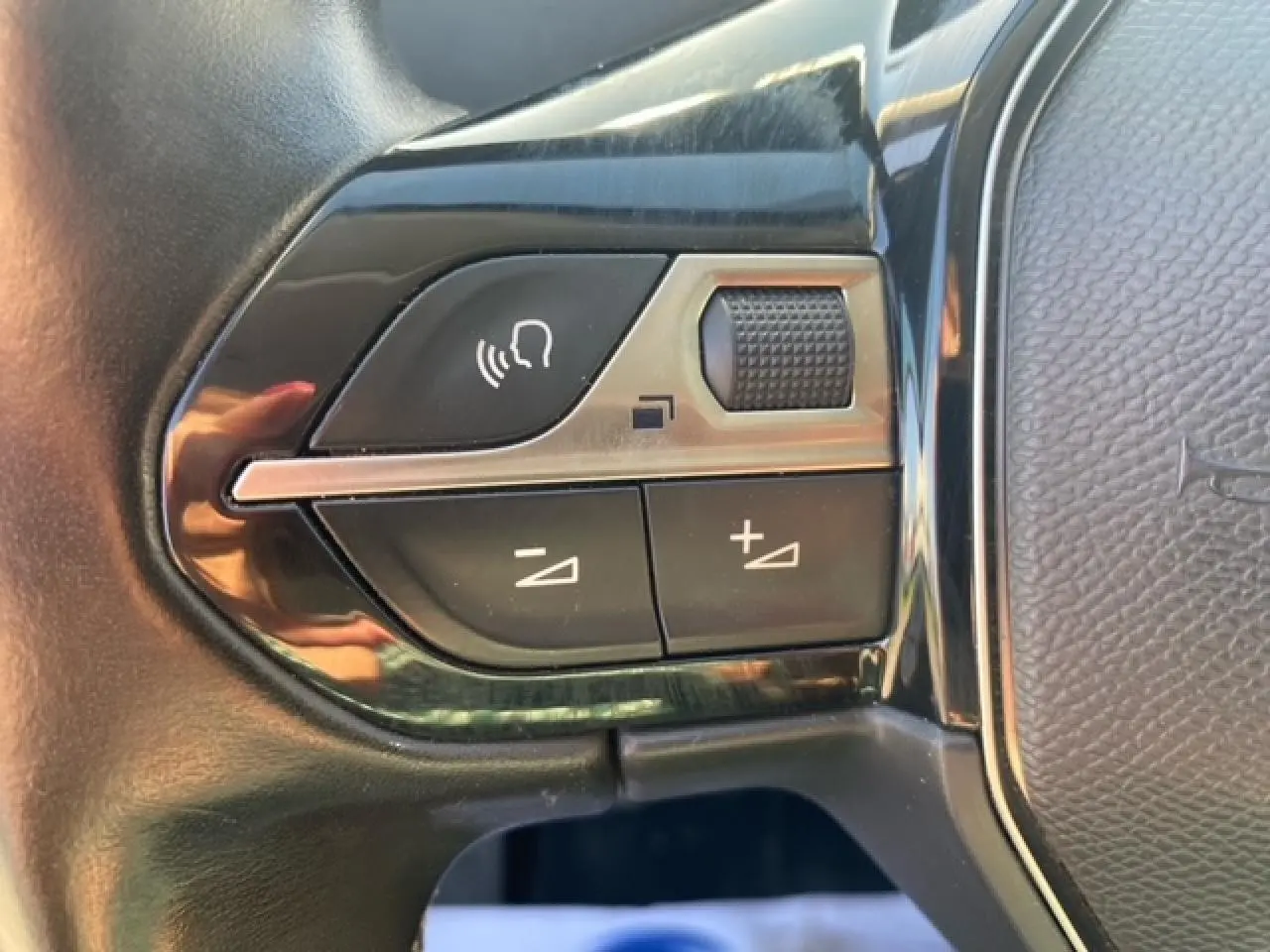 Gros plan sur les commandes de volume et voix du volant noir du Peugeot 3008 beige clair, version 2018.