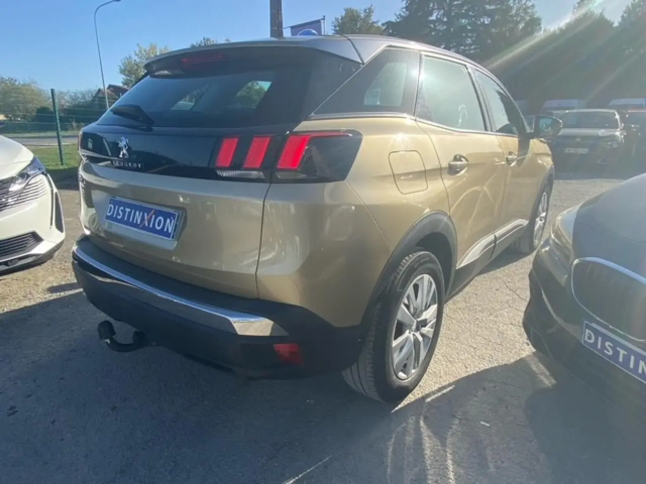 Vue 3/4 arrière droite d'un Peugeot 3008 beige clair avec attelage et jantes alliage 17 pouces, stationné en extérieur.