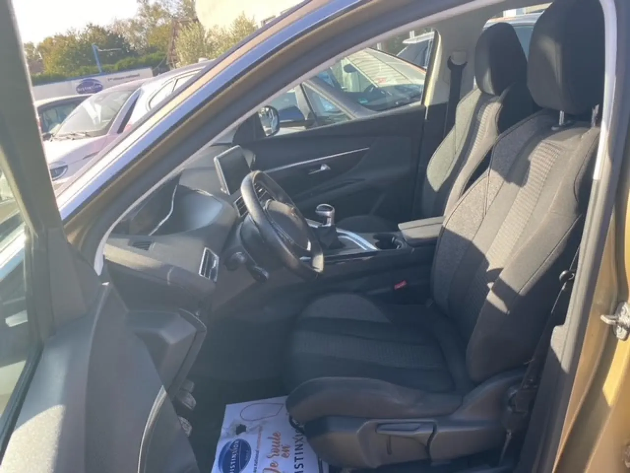 Vue intérieure côté conducteur du Peugeot 3008 beige clair, montrant les sièges tissu et le volant compact multifonctions.
