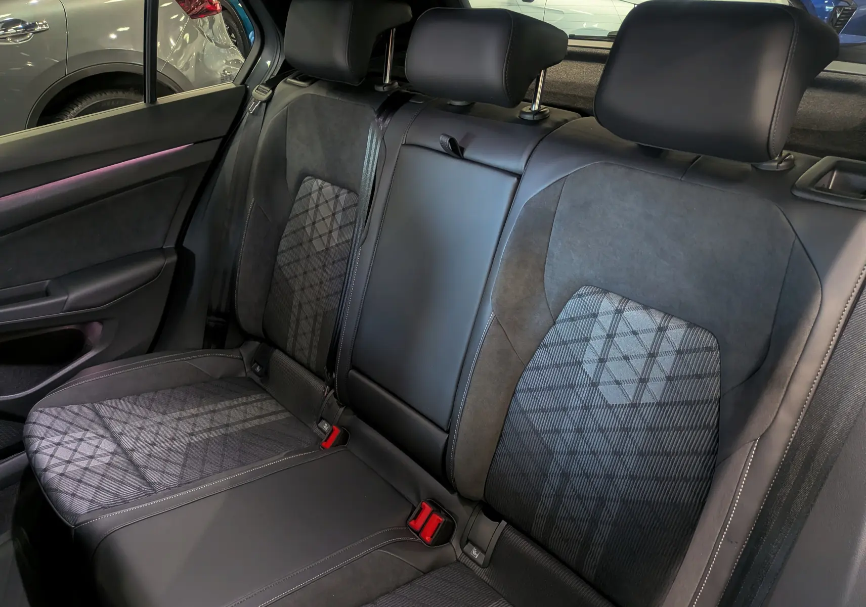 Vue intérieure des sièges arrière en tissu et cuir noir avec motifs géométriques dans une Volkswagen Golf VIII gris Urano.