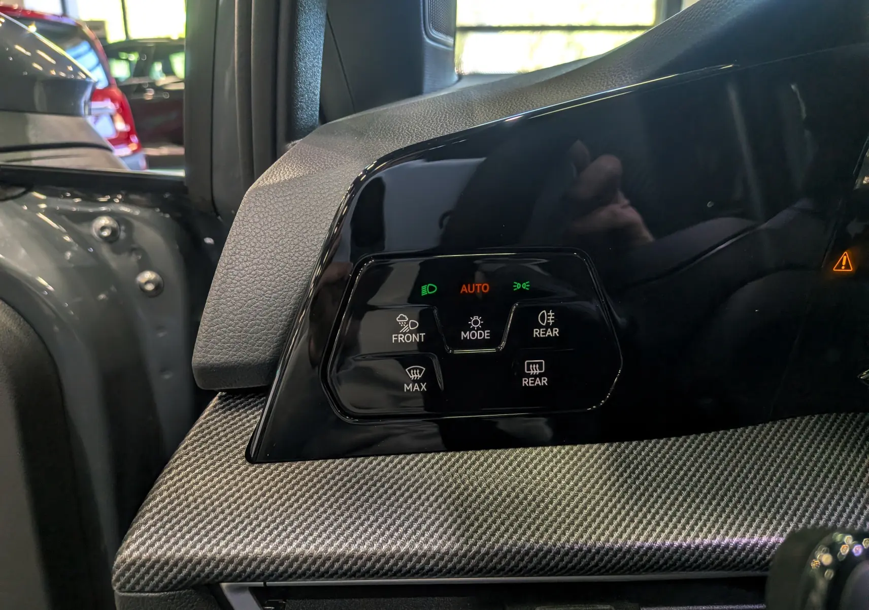 Gros plan sur le panneau de commande des phares et dégivrage, intérieur noir et gris de la Volkswagen Golf VIII R-Line.