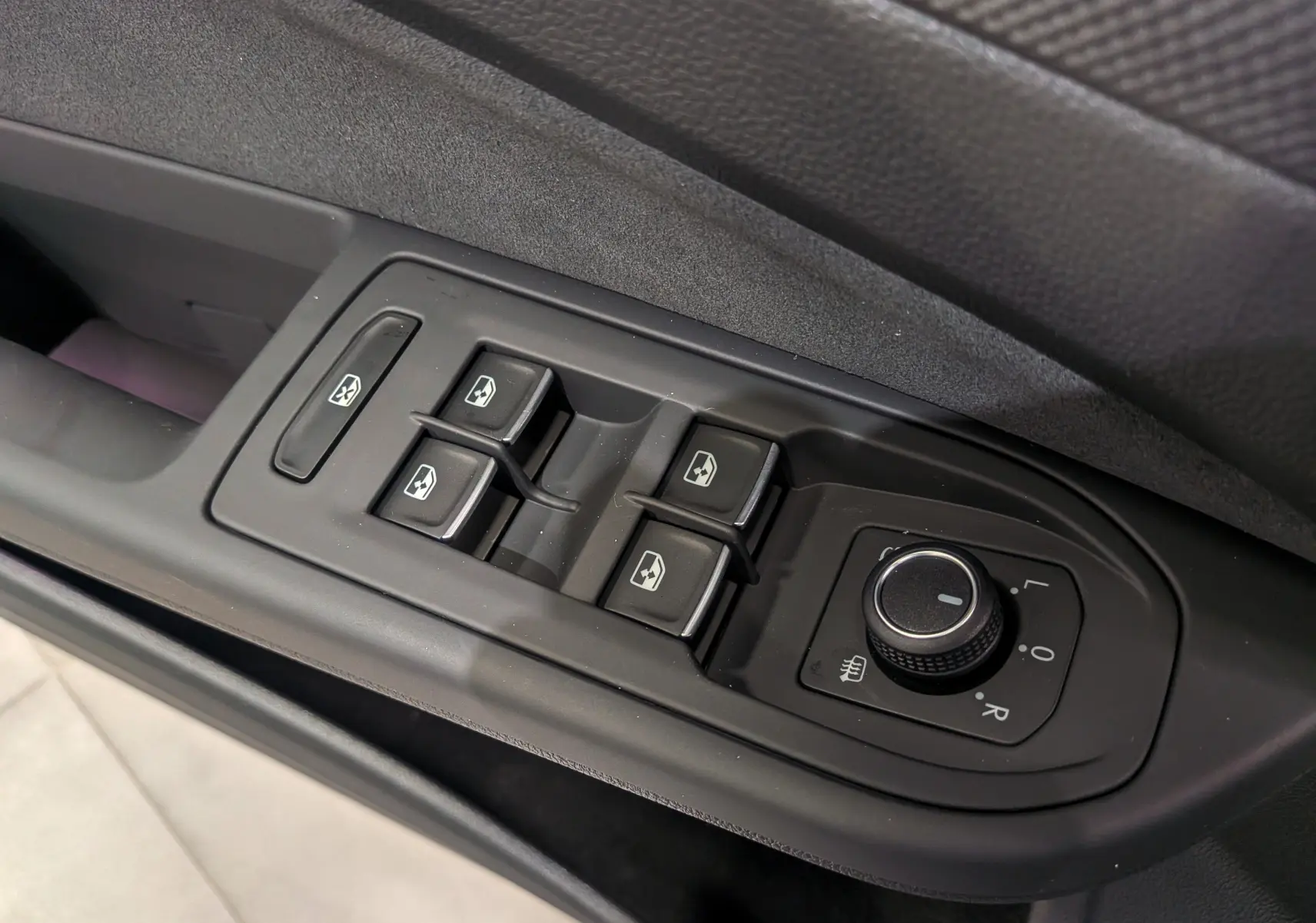 Gros plan sur les commandes de lève-vitres et rétroviseurs côté conducteur de la Volkswagen Golf VIII gris Urano.