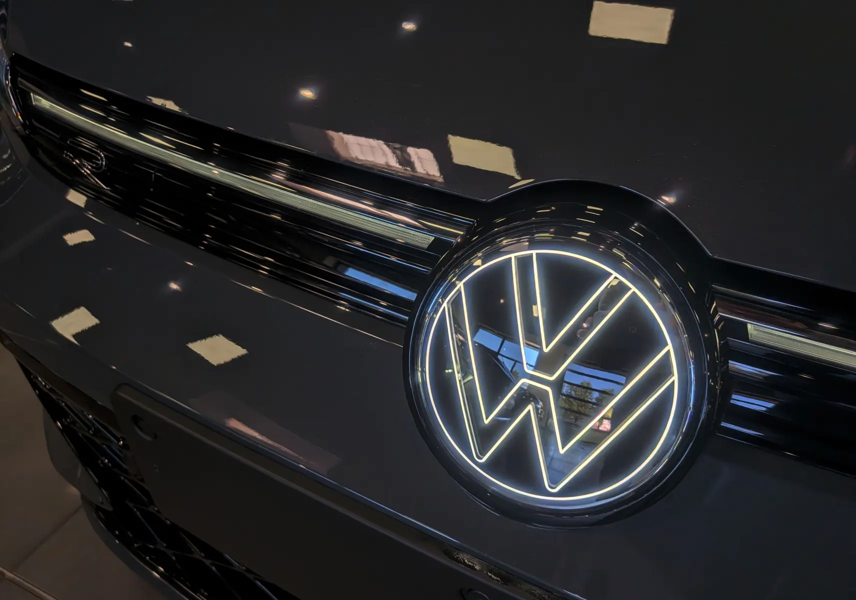 Gros plan sur la calandre avant gris Urano de la Volkswagen Golf VIII avec logo VW lumineux.