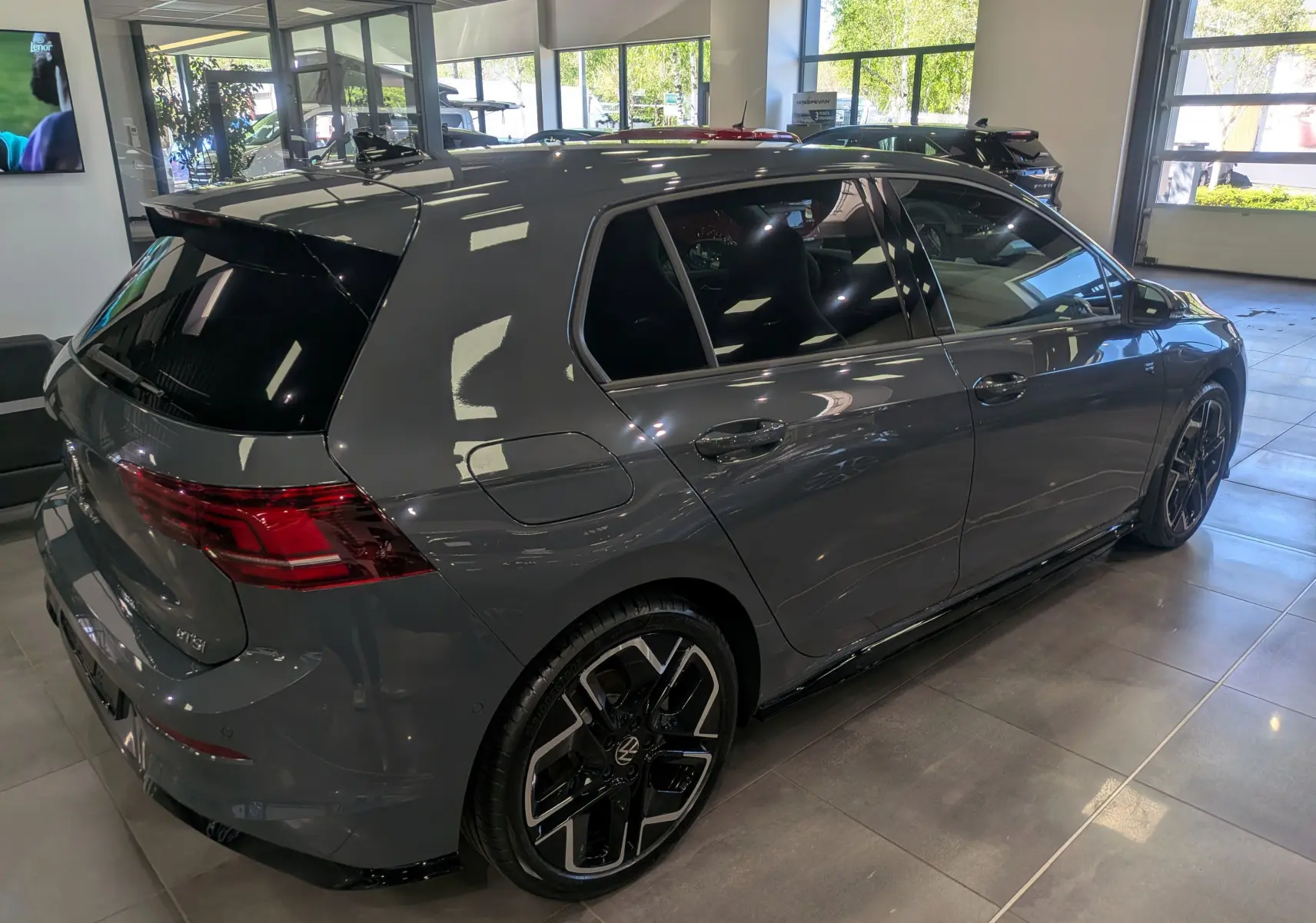 Volkswagen Golf VIII 1.5 eTSI R-Line gris Urano vue 3/4 arrière droit en intérieur, jantes noires bicolores.