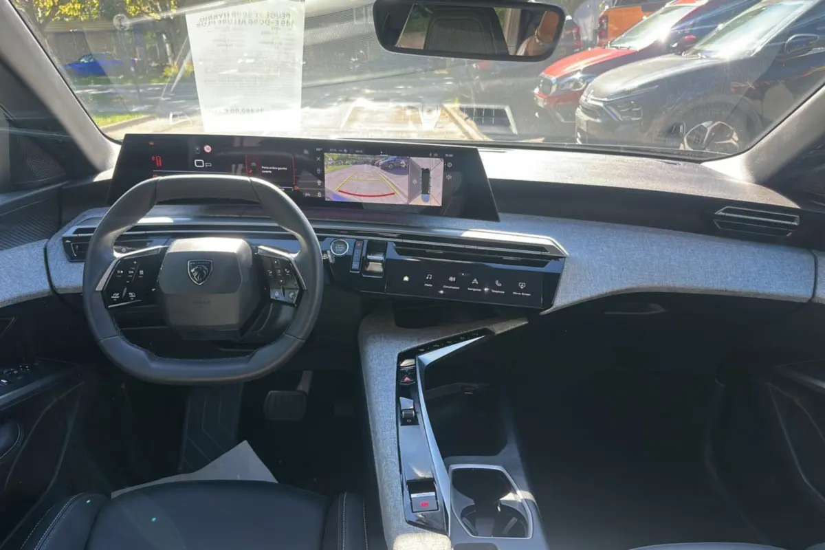 Vue intérieure avant du Peugeot 5008 Hybrid gris artense, avec tableau de bord numérique panoramique et volant cuir multifonctions.