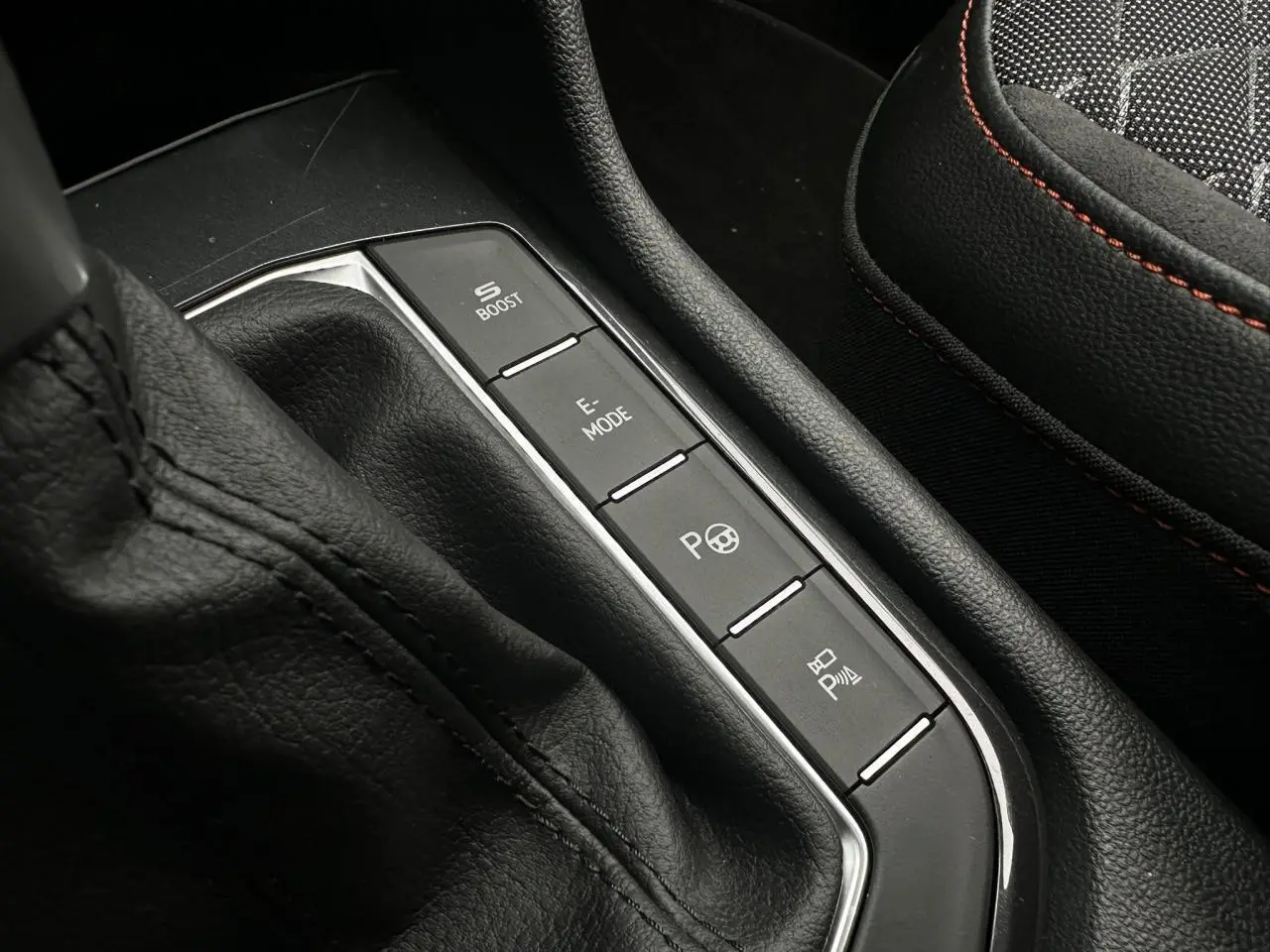 Gros plan sur la console centrale noire avec commandes de modes de conduite et siège sport noir avec surpiqûres rouges du SEAT Tarraco.