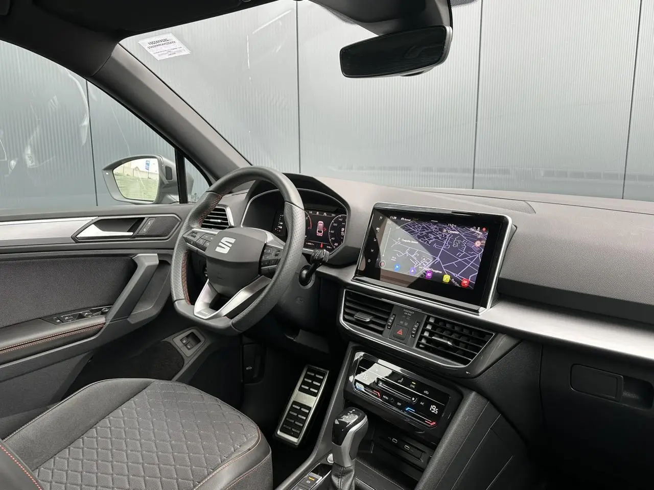 Intérieur côté conducteur du SEAT Tarraco blanc, volant cuir multifonction et écran tactile avec navigation visible.