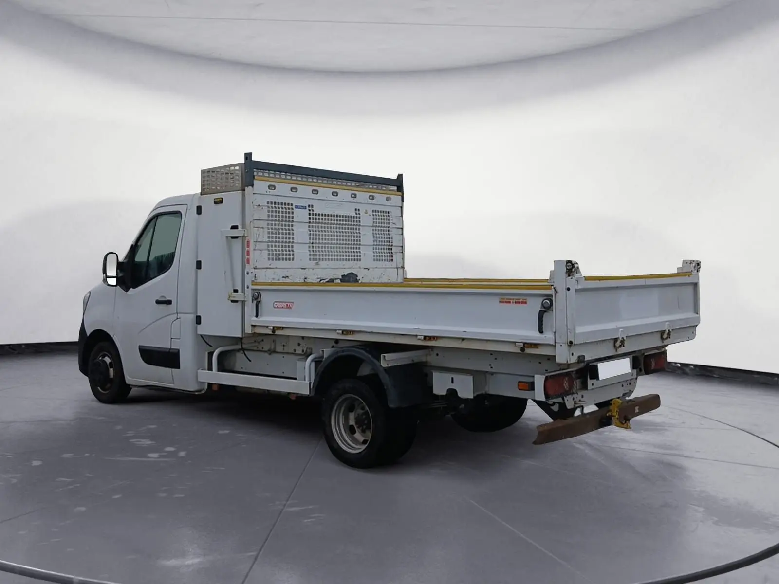 Renault Master blanc vu en 3/4 arrière droit, avec benne et coffre métallique sur plateau ouvert.