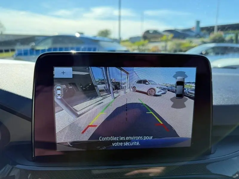 Écran de caméra de recul montrant l’arrière du Ford Kuga noir Agate, avec guidage de trajectoire coloré.