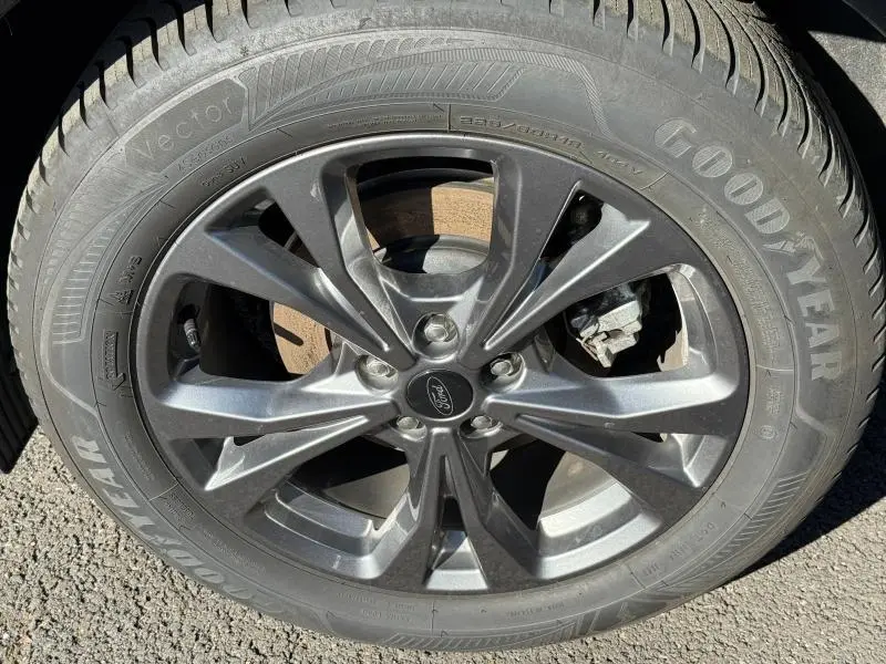 Gros plan sur la jante alliage grise du Ford Kuga 2024 avec pneu Goodyear Vector visible au soleil.