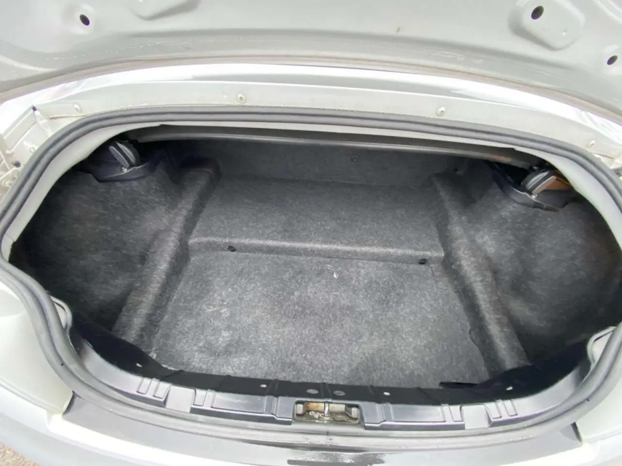 Coffre ouvert d’une BMW Z4 Roadster gris clair de 2005, vue arrière montrant l’espace de rangement vide.