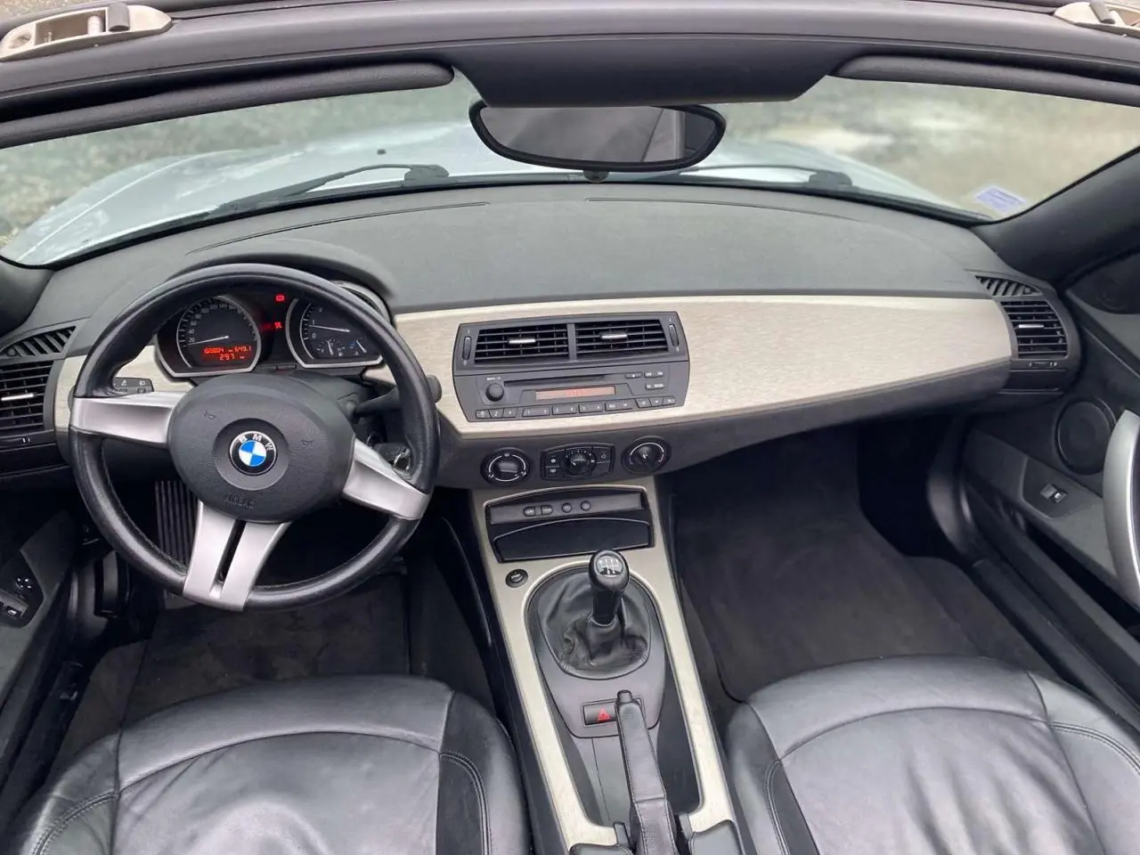 Vue intérieure avant de la BMW Z4 Roadster 2005, volant sport cuir, tableau de bord clair et levier de vitesse manuel.