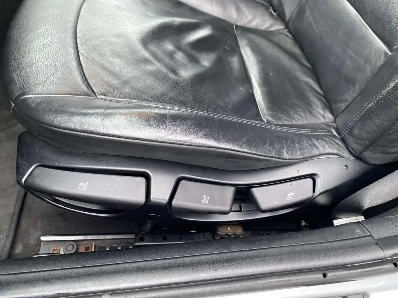 Gros plan sur les commandes de réglage du siège conducteur en cuir noir d'une BMW Z4 Roadster gris clair de 2005.