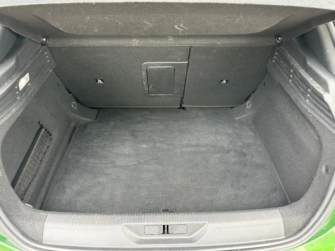 Coffre ouvert vu de face d’une Peugeot 308 2023 vert foncé, espace de chargement propre et vide.