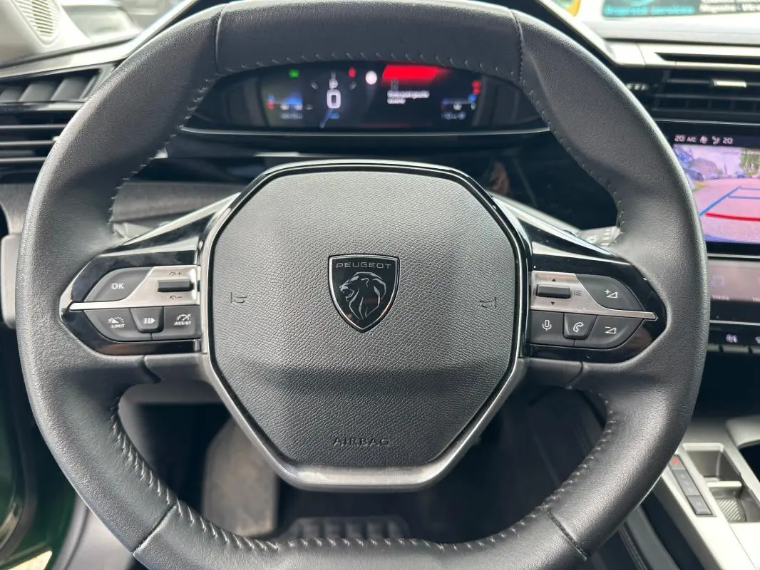 Vue rapprochée du volant noir de la Peugeot 308 2023 avec cockpit numérique et caméra de recul affichée.