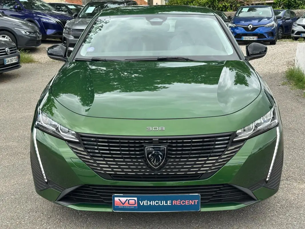 Vue frontale d'une Peugeot 308 2023 vert foncé avec calandre noire et feux LED verticaux distinctifs.