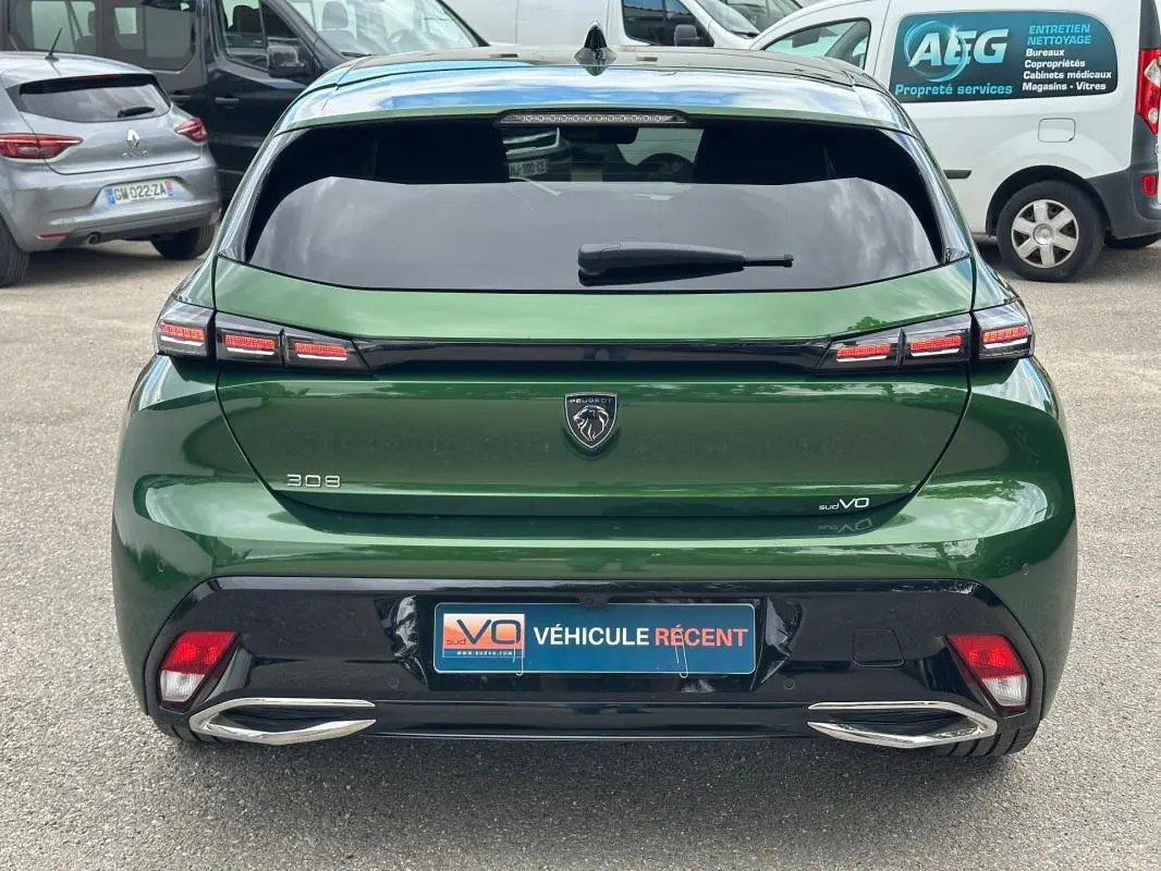Vue arrière d'une Peugeot 308 2023 vert foncé avec feux LED distinctifs et double sortie d'échappement chromée.