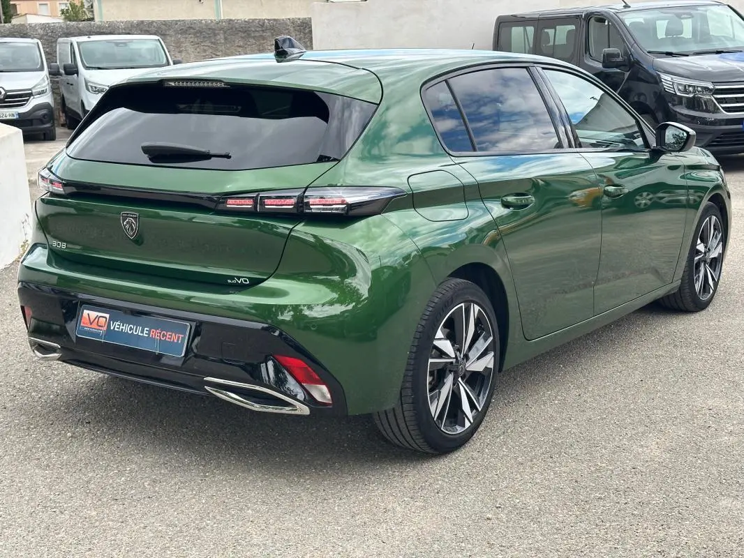 Vue 3/4 arrière droite d'une Peugeot 308 2023 vert foncé avec jantes alliage 17 pouces et vitres teintées.