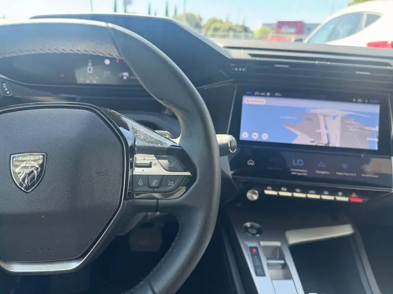 Vue intérieure centrée sur le volant noir et le cockpit numérique avec écran tactile de la Peugeot 308 gris 2025.