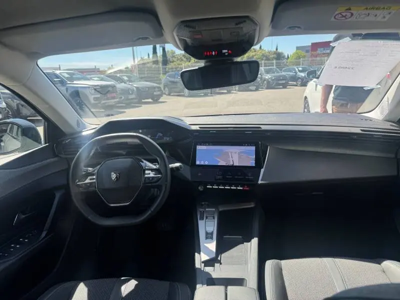 Vue intérieure avant du Peugeot 308 Hybrid 145 Allure 2025 gris, avec cockpit numérique et écran tactile central.