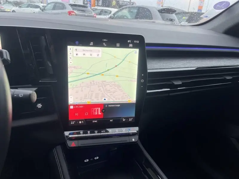 Tablette tactile centrale allumée avec navigation et ambiance lumineuse bleue dans l'habitacle du Renault Austral blanc.