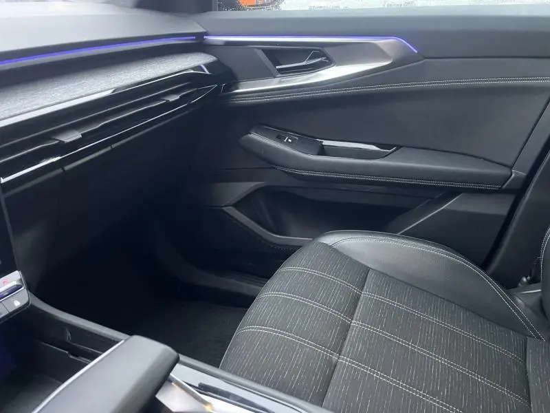 Vue intérieure côté passager du Renault Austral 2023, sièges gris et éclairage d'ambiance bleu subtil