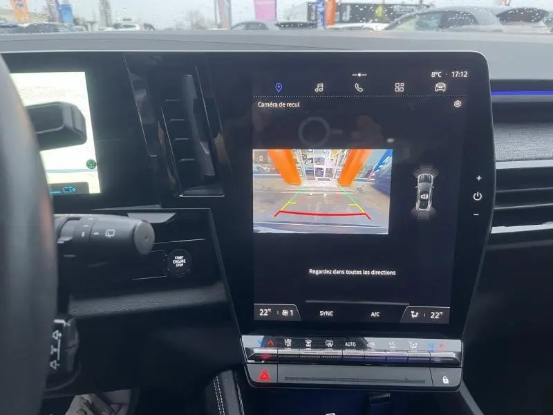 Vue intérieure du tableau de bord du Renault Austral blanc 2023, écran tactile affichant la caméra de recul et commandes climatisation.