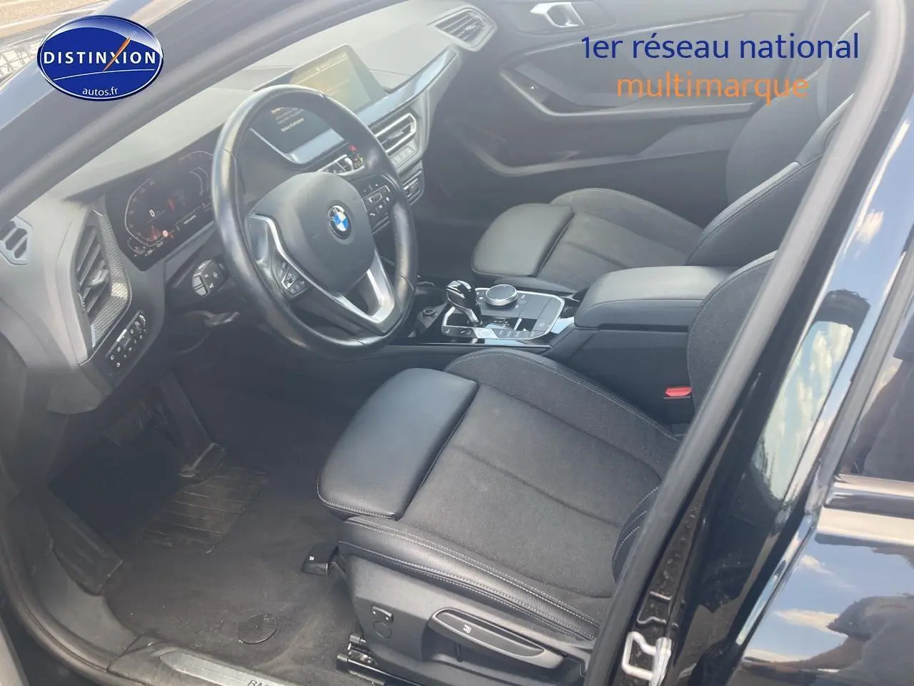Intérieur avant côté conducteur d'une BMW Série 1 noire 2023, sièges sport en tissu et cuir, volant multifonction cuir.
