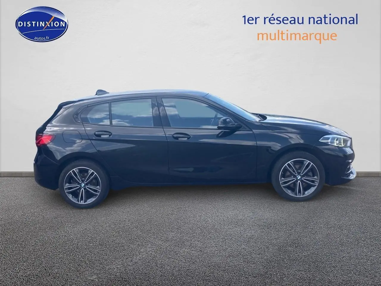 BMW Série 1 noire vue de profil côté gauche, avec jantes alliage et lignes sportives visibles.