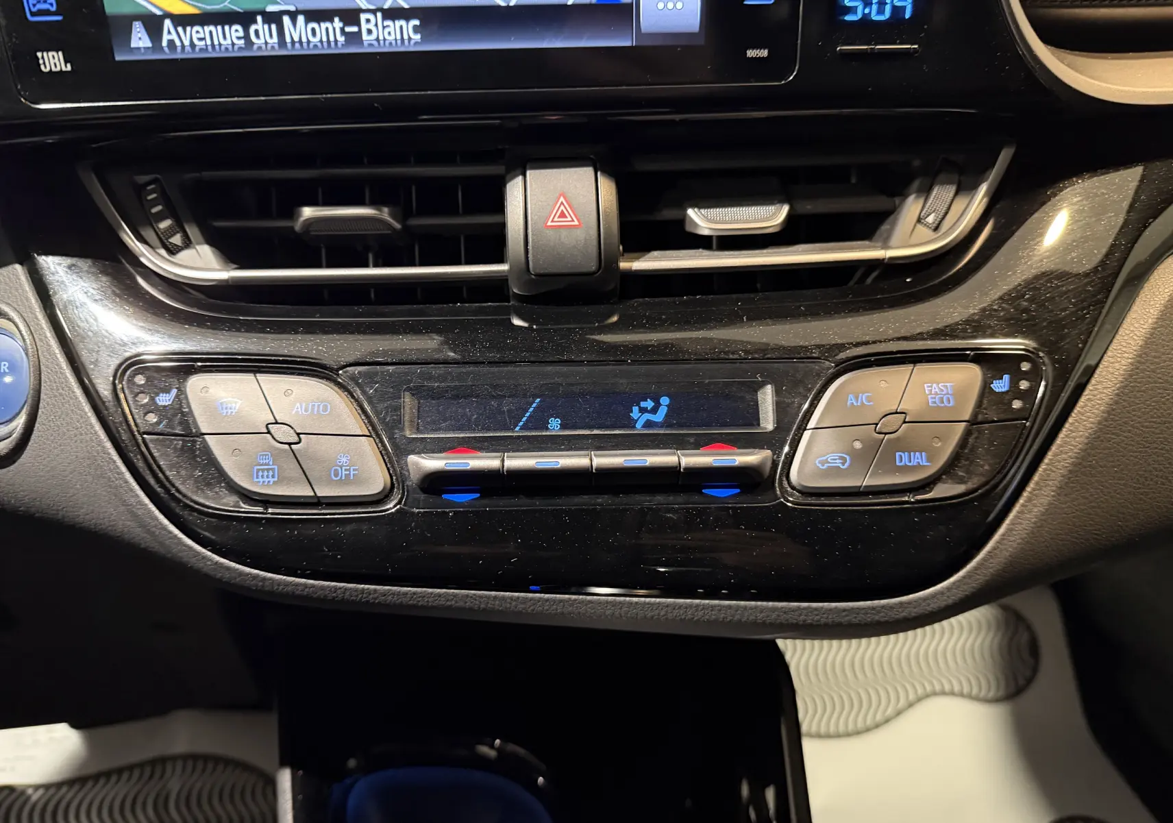 Vue rapprochée du tableau de bord central du Toyota C-HR Hybride rouge, montrant les commandes de climatisation et l'écran GPS.