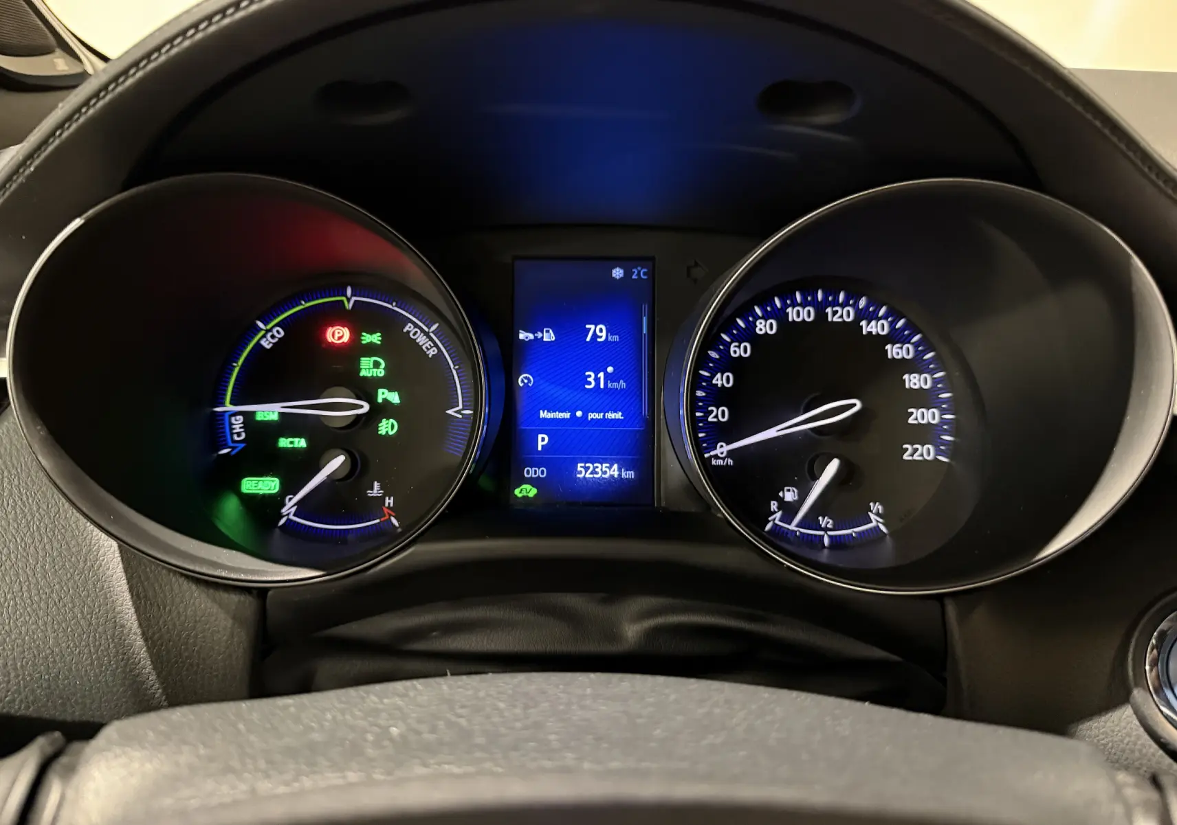 Vue rapprochée du tableau de bord du Toyota C-HR Hybride 2018, affichant les compteurs et l'écran digital bleu.