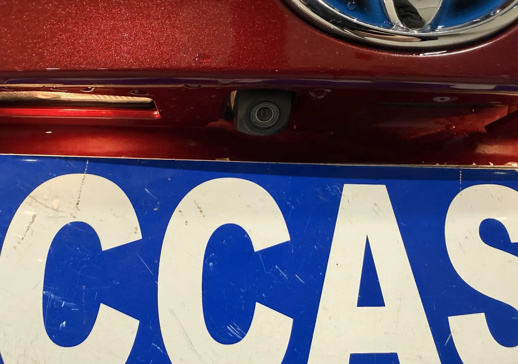 Gros plan sur la caméra de recul sous le logo Toyota, sur la face avant rouge du Toyota C-HR Hybride 2018.