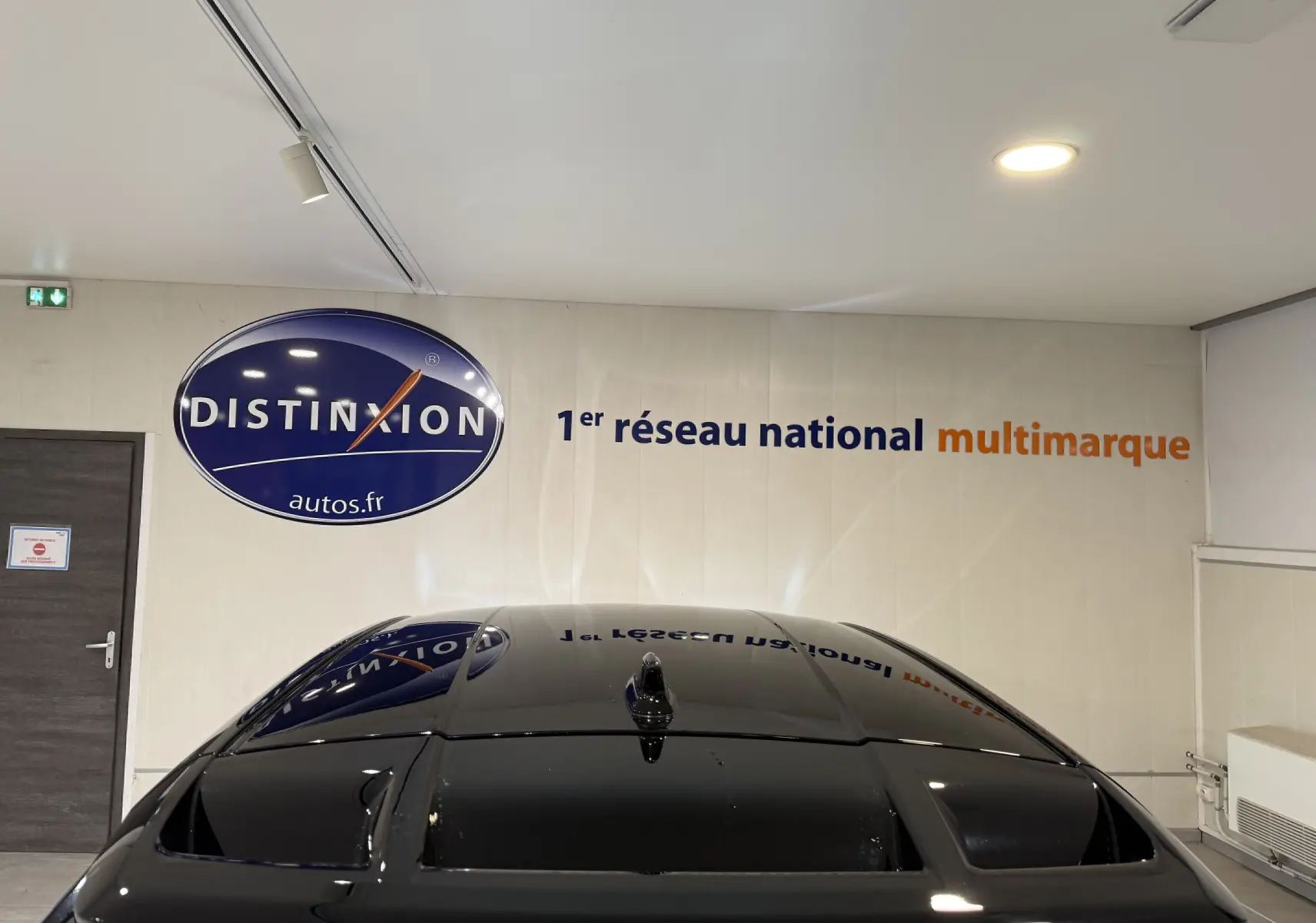 Toit panoramique noir brillant du Toyota C-HR Hybride rouge, vu de dessus en intérieur showroom.