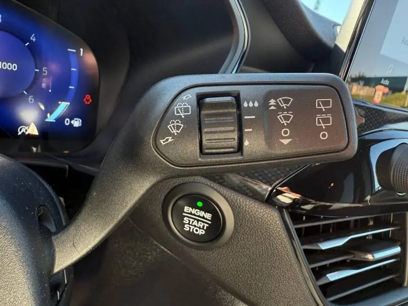 Gros plan sur la commande d’essuie-glace et bouton start/stop dans l’habitacle noir du Ford Kuga bleu 2024.